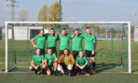 Zdjęcie grupowe drużyny Kompanii Prewencji 5 w zielonych koszulkach na tle bramki.