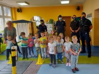 Ujęcie stojących policjantów z dziećmi i opiekunką.